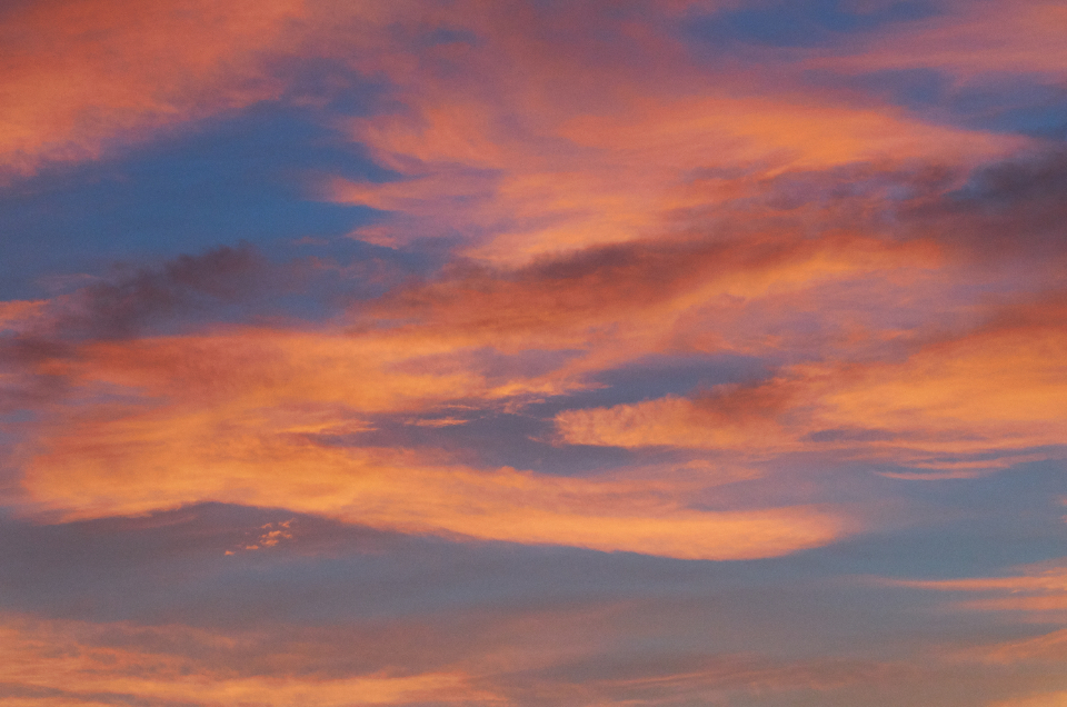 Bright sky filled with puffy peach and yellow clouds at dusk