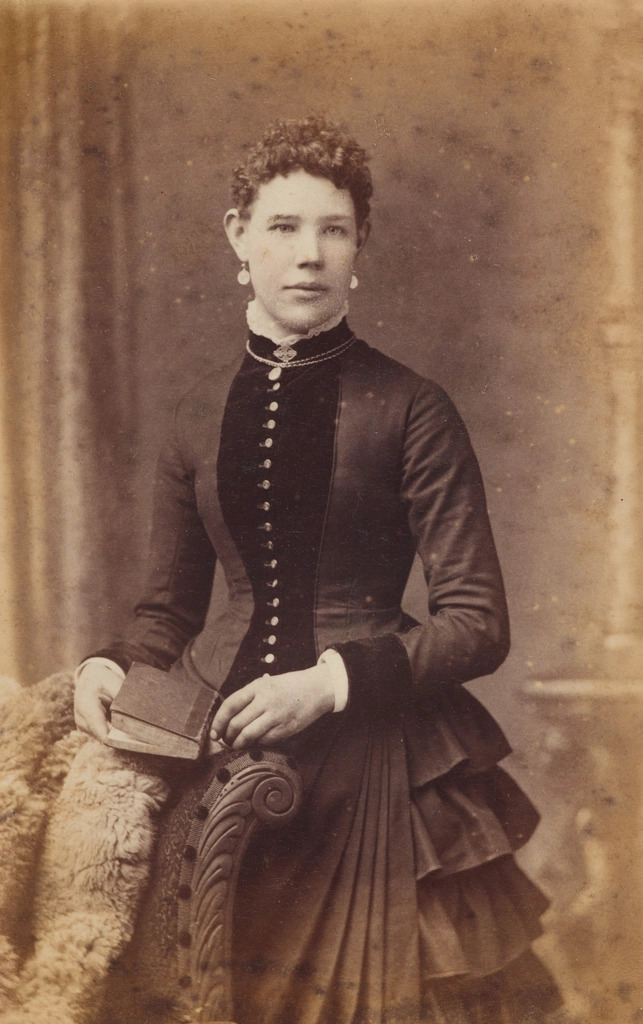 Open family photo album with faded colour prints held by corner mounts