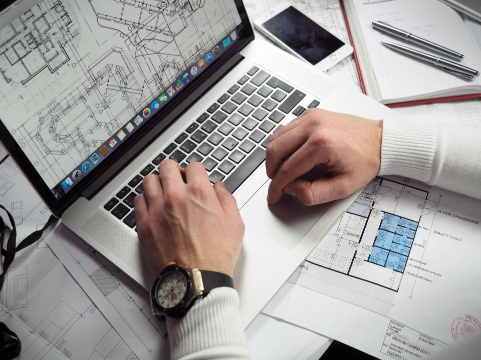 Architectural blueprints and drafting instruments spread across a work table
