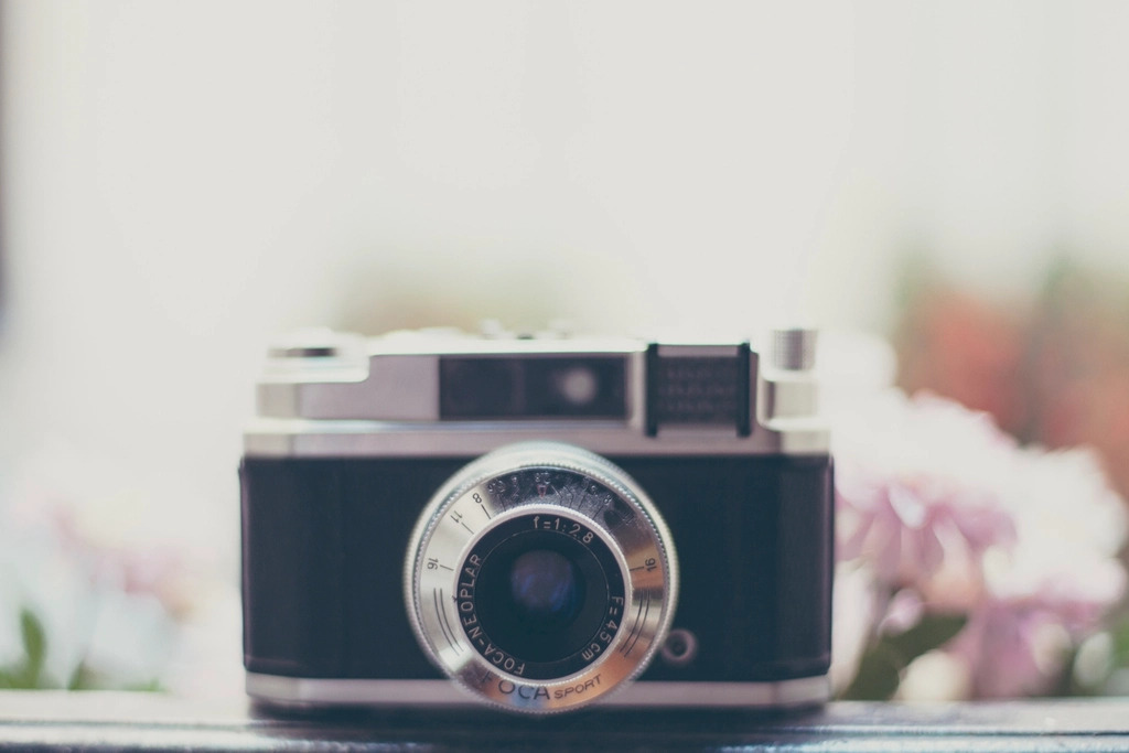 An old 35mm film camera resting on a dark wooden surface